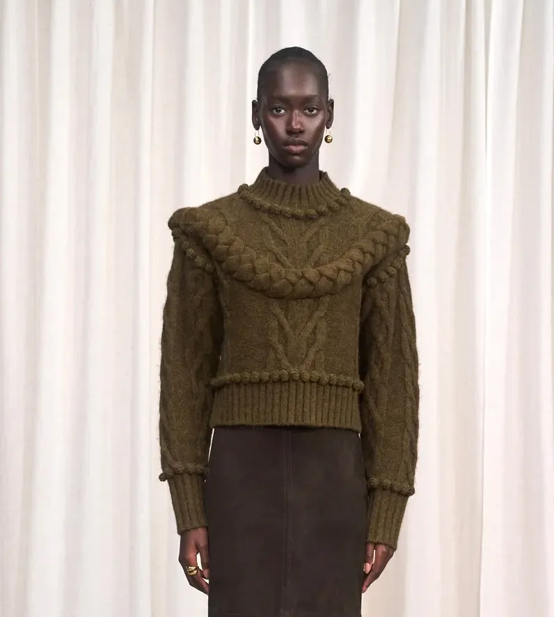 A model wears a textured olive green chunky knit sweater.