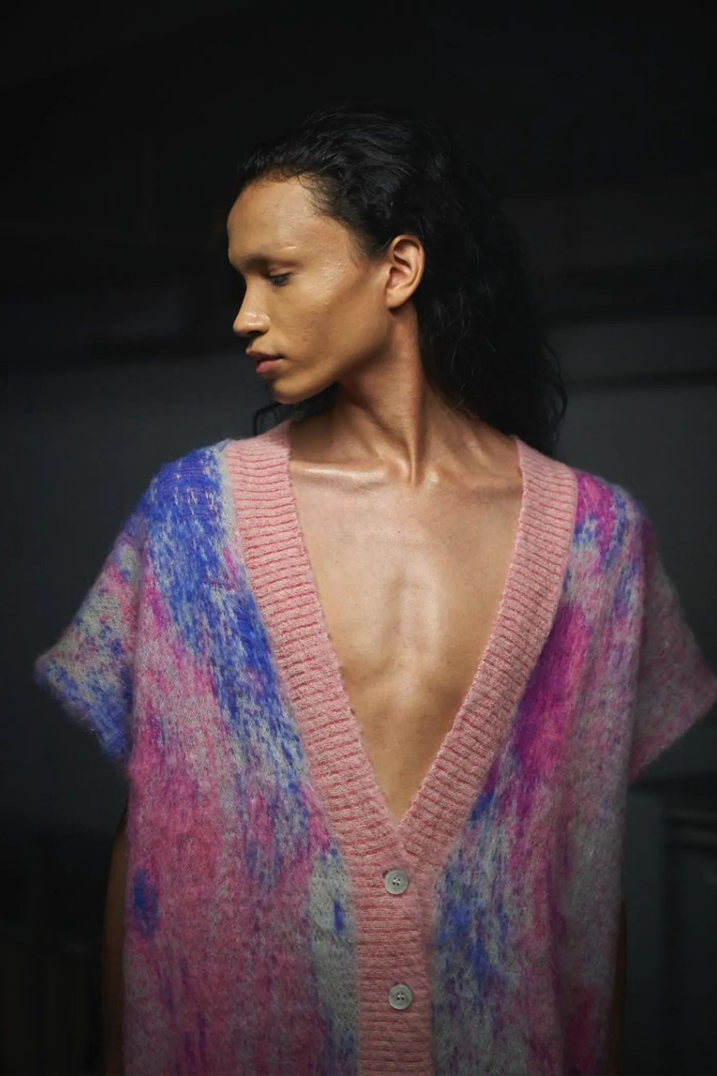 A person wears a fuzzy pink and blue mohair V-neck cardigan with abstract jacquard patterns and button closures.