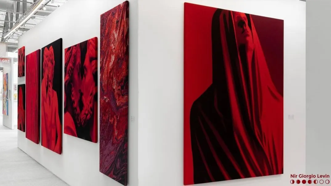 An art gallery with multiple knitted red and black abstract canvas art displayed on white walls.